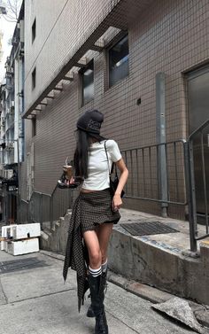 Woman in a plaid skirt and crop top walking on an urban street