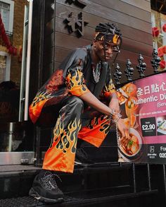 Person in a black and orange flame print outfit crouching outdoors