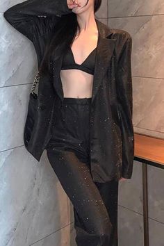 Woman in a sparkling black blazer and bra top with exposed midriff