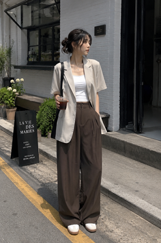 Woman in a short sleeve blazer and wide leg pants holding iced coffee on a street