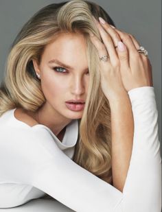 Woman with blonde hair and jewelry in a white top posing for a portrait