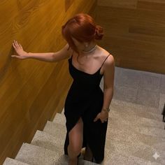 Woman in a black dress with a high slit walking down stairs
