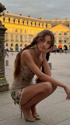 Woman with long hair in a mini dress and high heels squatting outdoors