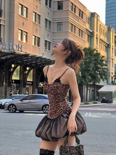 Woman in a leopard print dress and high socks on a city street at golden hour