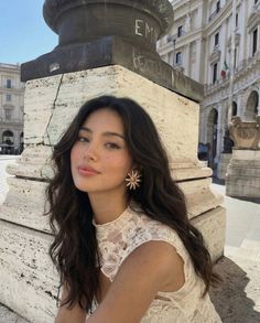 Woman with long dark hair and a lace dress outdoors in a city