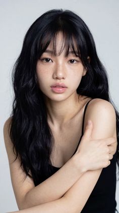 Woman with long black hair and freckles wearing a black tank top