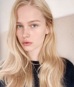 Woman with long blonde hair and blue eyes wearing a necklace