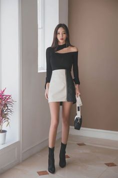 Woman with long hair wearing a black top and two-tone mini skirt indoors