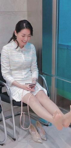 Woman in a white suit sitting and smiling indoors