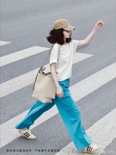 Person in a baseball cap and blue pants walking on a crosswalk