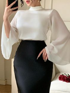Woman in a white blouse with bell sleeves and a black skirt, holding a phone