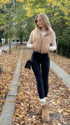 Woman with long blonde hair wearing a puffer vest and black leggings outdoors