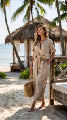 Woman in a beige outfit and sunglasses on a sandy beach