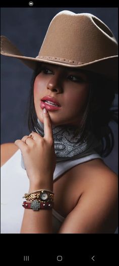 Woman in a cowboy hat and bandana with a finger to her lips