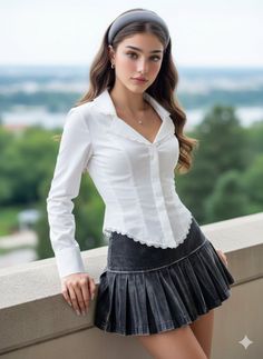 Woman with long hair and a headband wearing a white shirt and pleated skirt outdoors