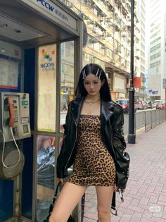 Woman in a leopard print dress and leather jacket on a city street