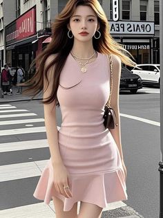Woman in a pink dress with long hair standing on a city street
