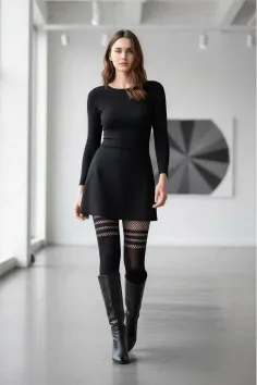 Woman in a black dress and fishnet stockings walking indoors