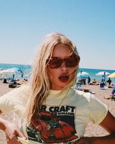 Blonde woman with sunglasses and a graphic t-shirt on a sunny beach