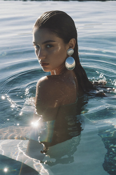 Woman with wet hair and large earrings in sparkling water