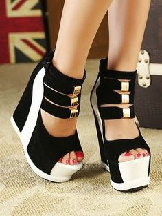 Close up of feet wearing black and white wedge heels with gold buckles