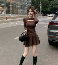 Woman in a brown dress with a cutout top and black boots on a street