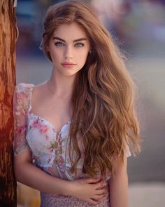 Woman with long hair and blue eyes wearing a sheer floral top