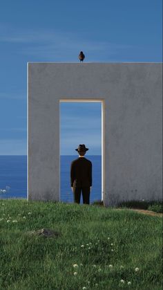 Man in a suit and fedora looking through a doorway at the ocean