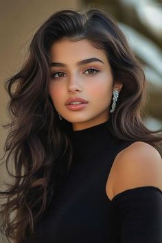 Woman with long dark hair and earrings wearing a black top