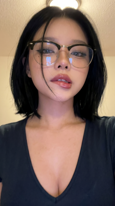 Woman with short black hair and glasses in a v-neck shirt with cleavage