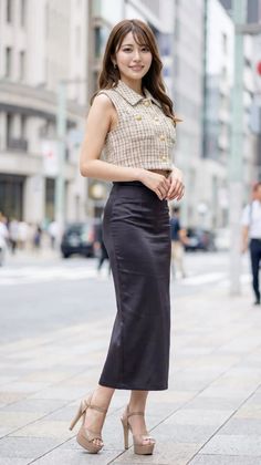 Woman in a tweed crop top and black midi skirt on a city street
