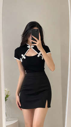 Woman in a black top and mini skirt taking a mirror selfie