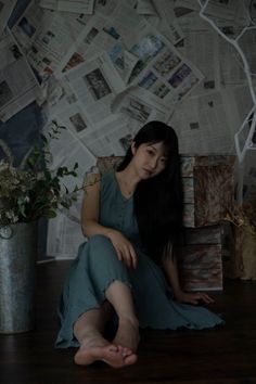 Woman with long black hair sitting on the floor in a sleeveless dress