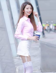 Woman in a pink shirt and white skirt with thigh-high stockings holding a cup