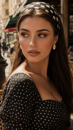 Woman in a polka dot dress and headband looking to the side outdoors