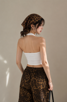Woman in a leopard print bandana and white halter top, seen from behind