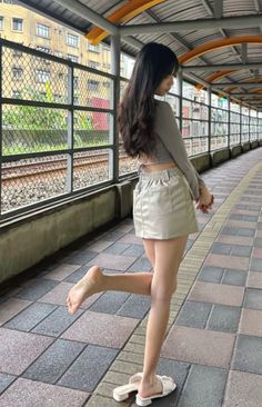 Woman in a crop top and mini skirt posing at a train station