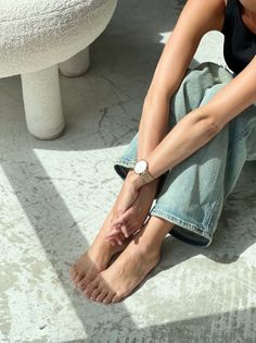 Person sitting on a concrete floor with bare feet and jeans