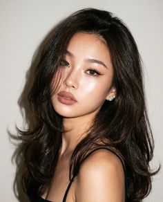 Woman with long dark hair and soft lighting looking at the camera