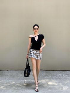 Woman in a black top and plaid mini skirt walking outdoors