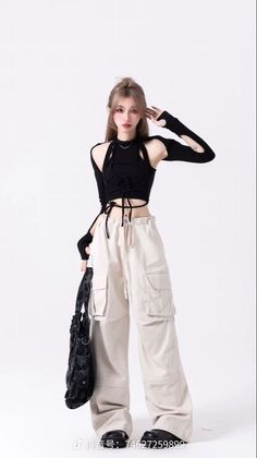 Woman in a black crop top and cargo pants posing against a white background
