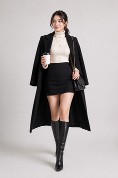 Woman in a black coat, turtleneck, and mini skirt holding a coffee cup