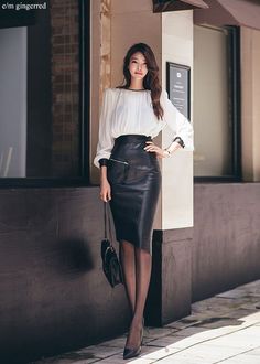Woman in a white blouse and black leather skirt posing outdoors
