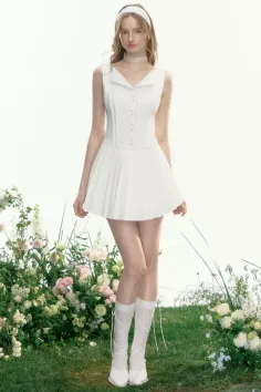 Woman in a white dress and knee-high socks standing in a garden