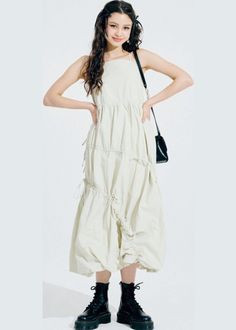 Woman with long hair wearing a midi dress and black boots in a studio