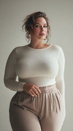 Woman with curly hair wearing a long sleeve shirt and beige pants