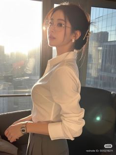 Woman in a white shirt and glasses with a cityscape in the background at golden hour
