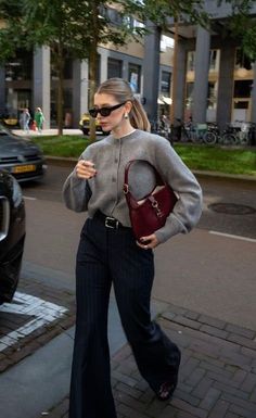 Woman in a grey cardigan and flared pants walking on a city street