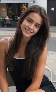 Smiling woman with long brown hair wearing a black dress outdoors