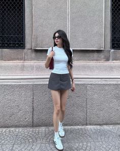 Woman with long dark hair wearing a white t-shirt and mini skirt on a street